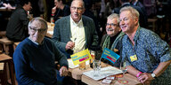 Vier Männer sitzen an einem Tisch auf FDP-Fähnchen stehen