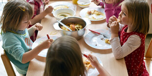 Kinder sitzen um einen Tisch und essen