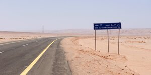 Eine Strasse und ein Strassenschild in der Wüste
