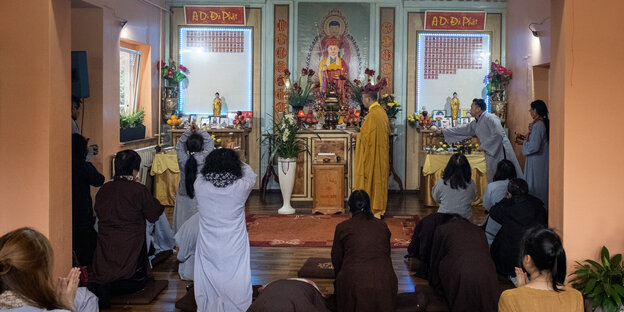 Menschen knien in einem buddhistischen Gotteshaus