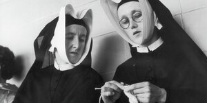 Zwei Nonnen sitzen auf einer Bank, eine strickt