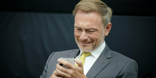 Christian Lindner schaut auf sein mobiltelefon