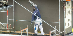 Ein Arbeiter verputzt eine Wand mit Wärmeisolierung