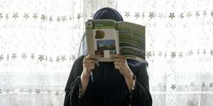 Ein Mädchen in einer Untergrundschule in Afghanistan hält sich ein Lehrbuch vors Gesicht
