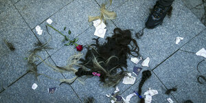 Abgeschnittene Haare und Rosen und zerrissene Zettel liegen auf dem Boden