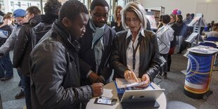 Eine Frau spricht mit zwei Männern bei einer Berufsorientierungsbörse