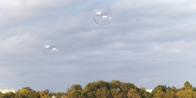 Kaum sichtbar schweben farblose Luftballone vor grauem Himmel über der verwilderten Galopprennbahn im Bremer Stadtteil Vahr