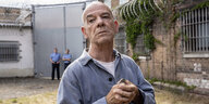 Dr. Adrian Goser steht in einem Gefängnishof mit vor der Brust gefalteten Händen.