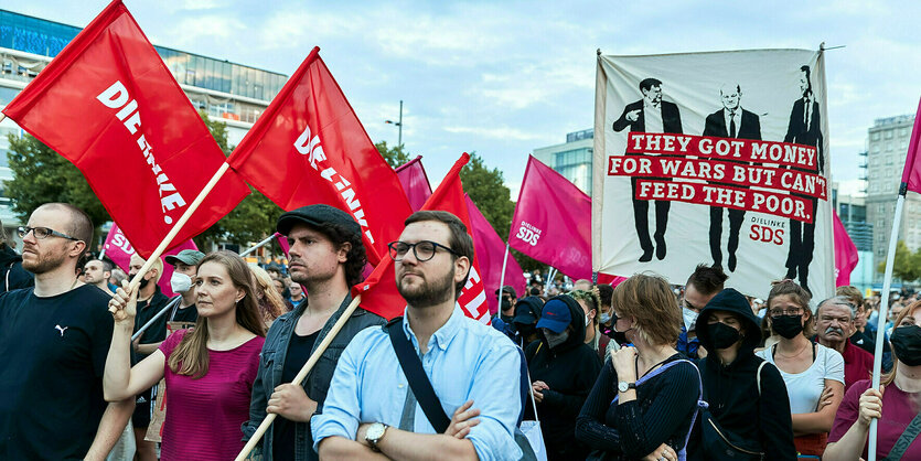 Menschen demonstriere, einige tragen Fahnen der Partei "Die Linke"