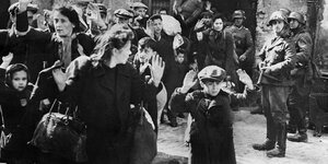 Bewaffnete Nazis treiben Juden, die erschrocken die Hände heben, aus dem Warschauer Ghetto