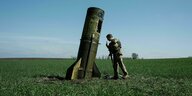 Ein ukrainischer Soldat betrachtet eine russische Rakete, die in einem Feld eingeschlagen ist