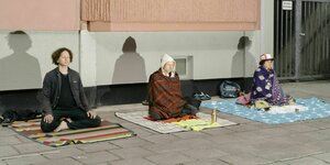 Menschen meditieren auf der Straße während einer Corona Demonstration