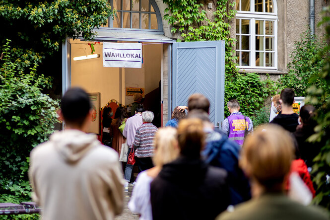 Menschen stehen Schlange vor einem Wahllokal