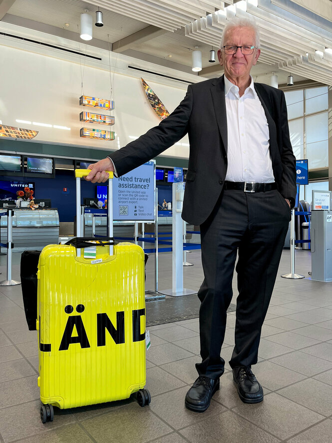 Mann mit gelben Koffer an einem Flughafen