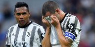 Juve-Profi Bonucci hält sich das Trikot vors Gesicht, Mitspieler Sandro schaut betroffen drein