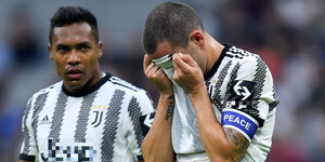Juve-Profi Bonucci hält sich das Trikot vors Gesicht, Mitspieler Sandro schaut betroffen drein