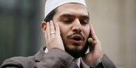 Der Muezzin Mustafa Kader, ein junger Mann, die Augen halb geschlossen, die Hände an den Wangen, singt in ein Mikrofon