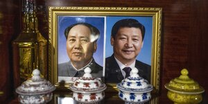 Im goldeneen Bilderrahmen ein Doppelportrait von Mao Tsetung Xi Jinping
