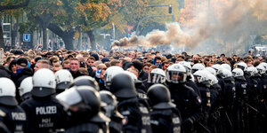 Behelmte Polizisten vor einer Menge von Fußballfans