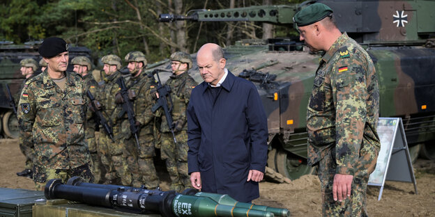 Olaf Scholz lässt sich von bundeswehrangehörigen in Uniform militärische Ausrüstung zeigen