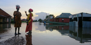 Zwei Frauen stehen auf einer überfluteten Dorfstrasse