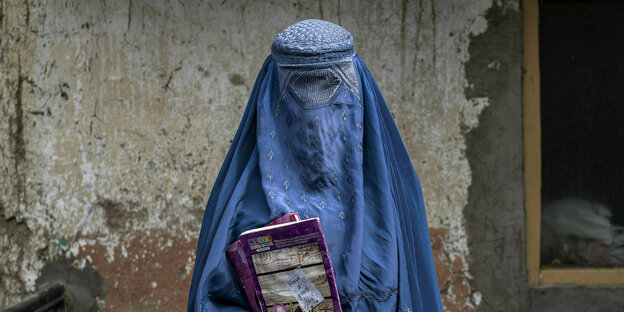 Eine Frau mit Burka, hält ein Buch in der Hand