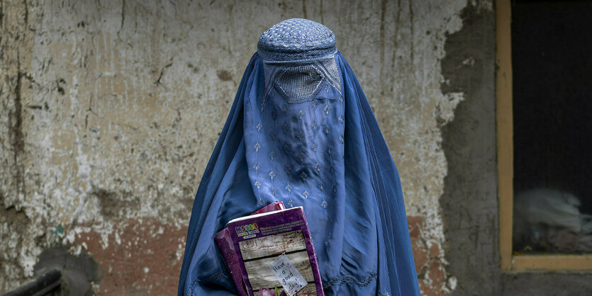 Eine Frau mit Burka, hält ein Buch in der Hand