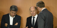 Wirtschaftsminister Robert Habeck, Olaf Scholz und Christian Lindner stehen vor einem organgefarbenem Hintergrund und unterhalten sich