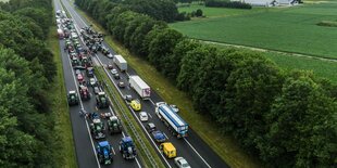 Lastwagen und Trecker blockieren eine vierspurige Straße - Blick von oben