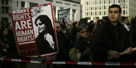 Protest mit Schild auf dem das Foto von Mahsa Amini zu sehen ist