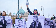vier frauen halten Bilder von getöteten Iranischen Frauen hoch, eine hebt die Hand, im Hintergrund der Berliner Dom