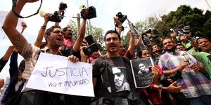 Mexikanische Journalist:innen protestieren mit erhoben Kameras und Transparenten gegen den Mord an einem ihren Kollegen.