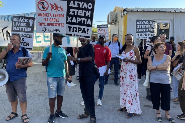 Männer und Frauen halten Protestplakate und ein Megafon