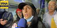 Elnaz Rekabi spricht umringt von Menschen in ein Mikrophon