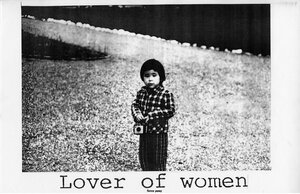 Schwarz-weiß Fotografie: Ein Kind steht in einem Park und blickt in die Kamera, in der Hand trägt es eine Kamera