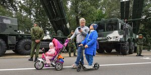 Mutter mit zwei Kindern vor Armeefahrzeugen