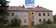 Ein Wahlplakat der AfD hängt vor einem verlassenen Wohnhau