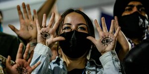 Aktivisten halten ihre Handinnenflächen hoch auf die jeweils ein schwarzes Auge gemalt ist