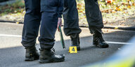 Die Beine von zwei Polizisten, dazwischen ein gelber Aufsteller mit der Zahl vier