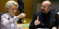 Das Bild zeigt EU-Kommissionschefin beim Klingeln einer Glocke im Gespräch mit Charles Michel, Präsident des Europäischen Rates, der den Zeigefinger erhoben hat.