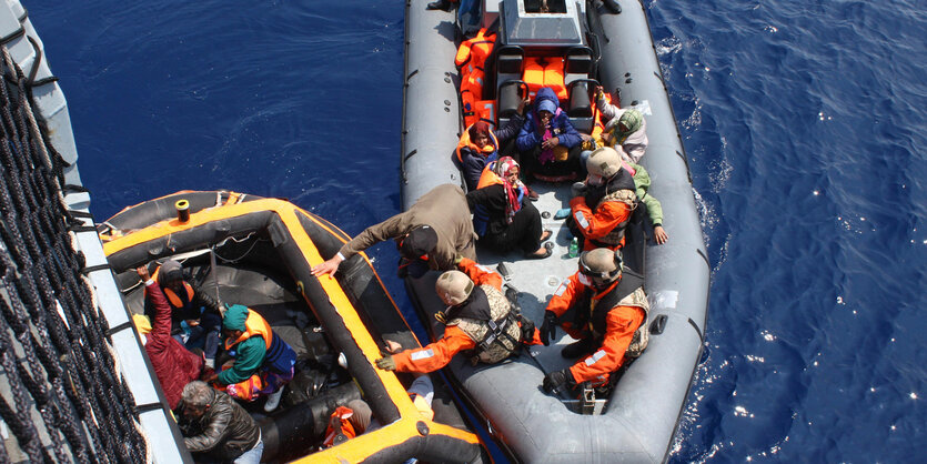 Menschen werden aus einem kleinen Boot auf ein größeres Schiff gebracht