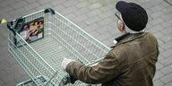 Ein Senior schiebt einen leeren Einkaufswagen