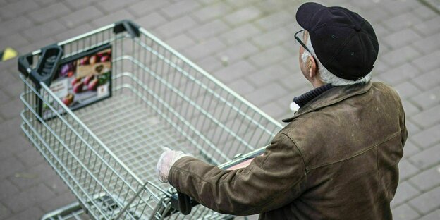 A senior pushes an empty shopping cart