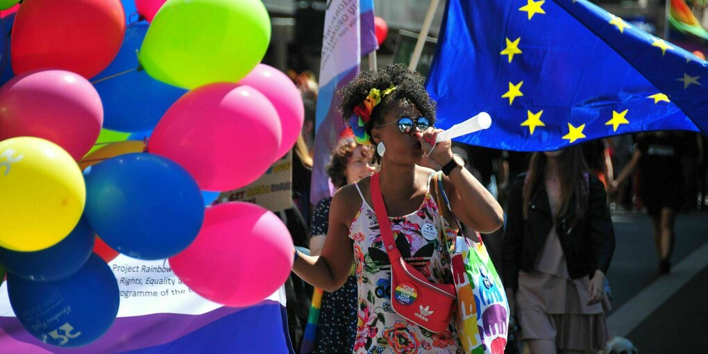 eine Frau steht vor bunten Ballons und EU Flagge