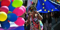 eine Frau steht vor bunten Ballons und EU Flagge