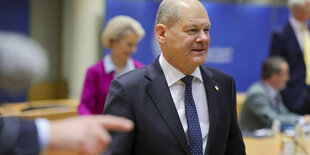 Olaf SCholz, vor ihm zeigt ein Finger nach rechts, hinter ihm ist Ursula von der Leyen