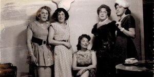 Historische Aufnahme von fünf Personen in Frauenkleidern.