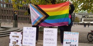 Zwei Menschen halten eine Pride-Flagge hoch