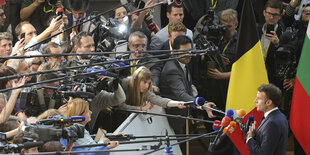 Vor Emmanuel Macron stehen sehr viele Journalisten und halten ihre Mikrophone vor ihn