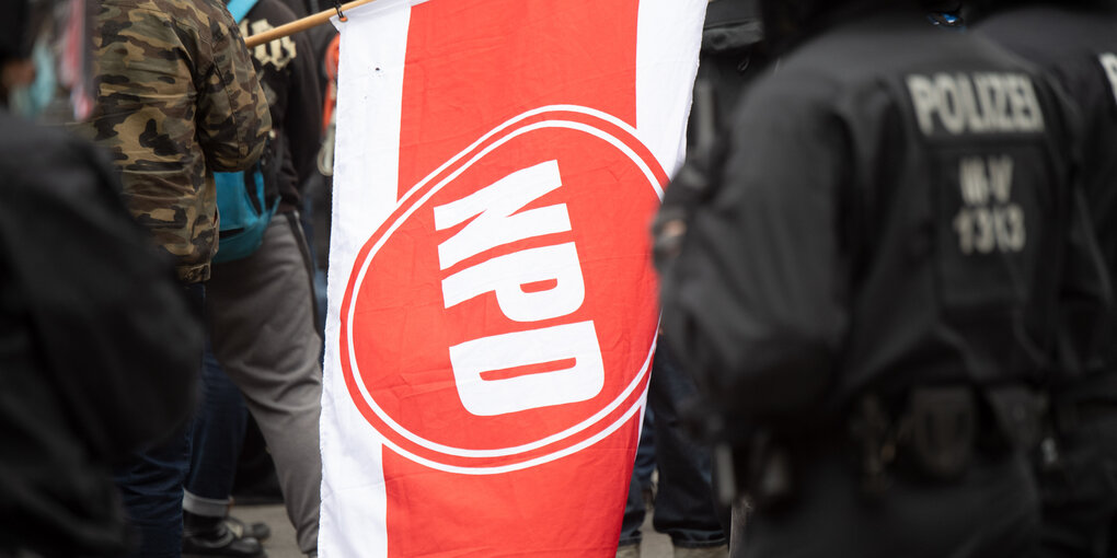 Flagge der NPD, daneben ein Polizist